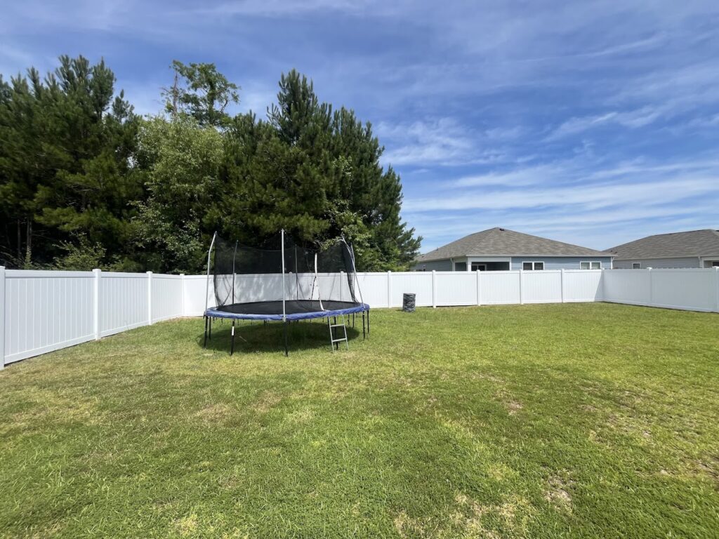 White vinyl privacy fence with trampoline in backyard